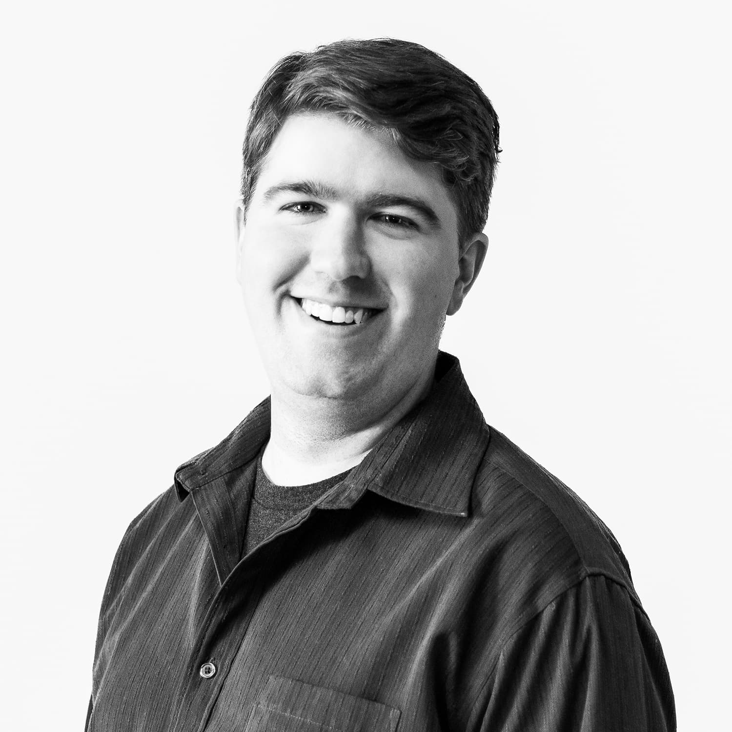 A grayscale image of Jamieson Roberts in a dark collared shirt appearing in front of a white background wall.